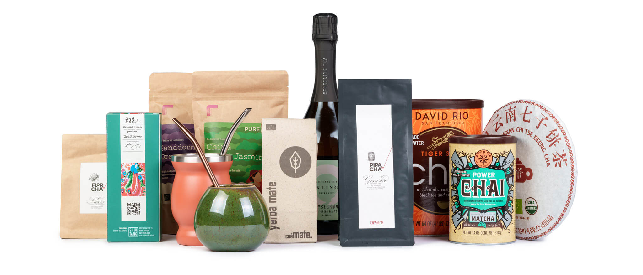 Vielfältige Auswahl internationaler Tees und Teezubehör, darunter Mate, Chai, Jasmin- und Pu Erh-Tee, dekorativ arrangiert.