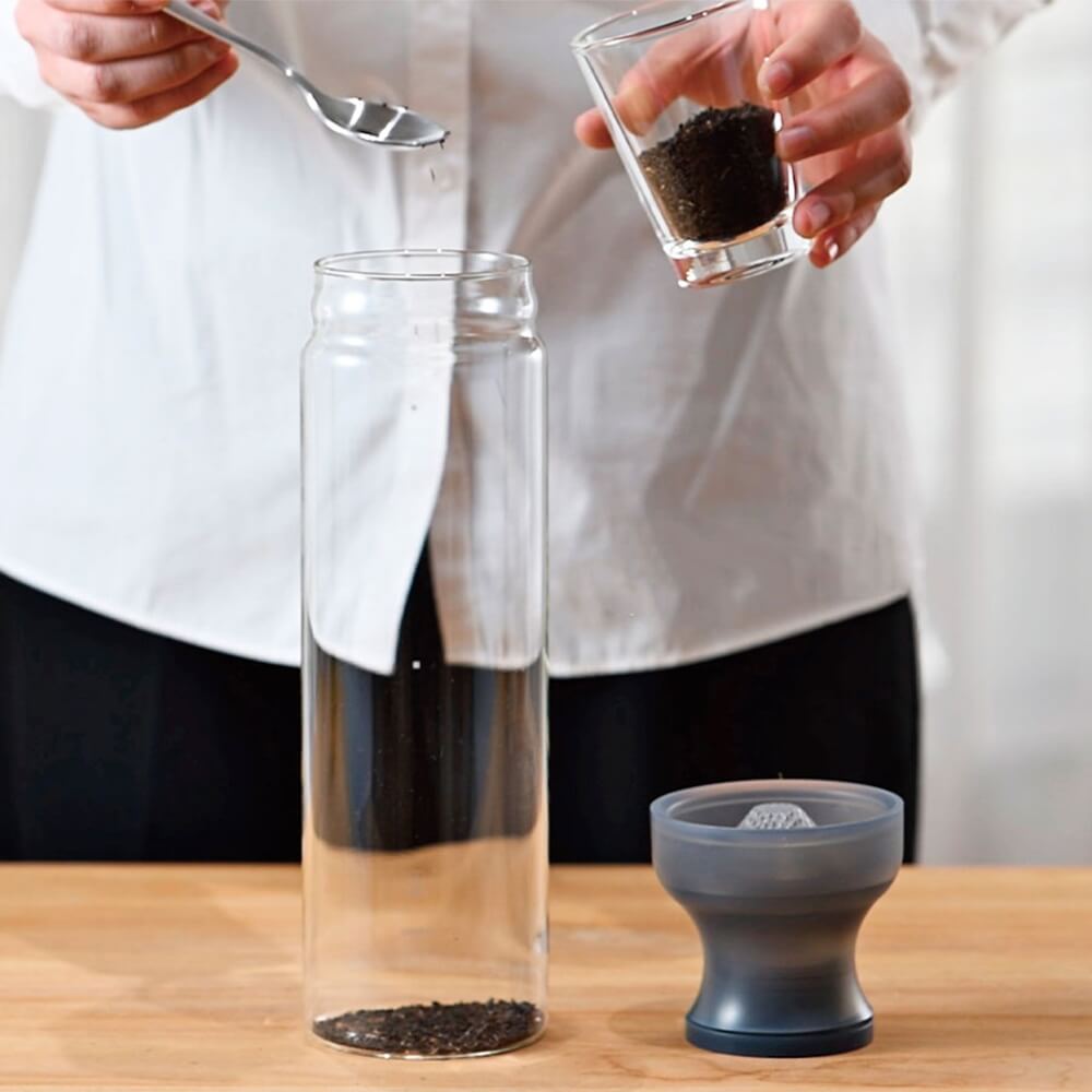 Zubereitung von Cold Brew Tee in der Hario Teeflasche grau mit Filter, loser Tee wird in die Glasflasche gegeben#teeflasche_grau