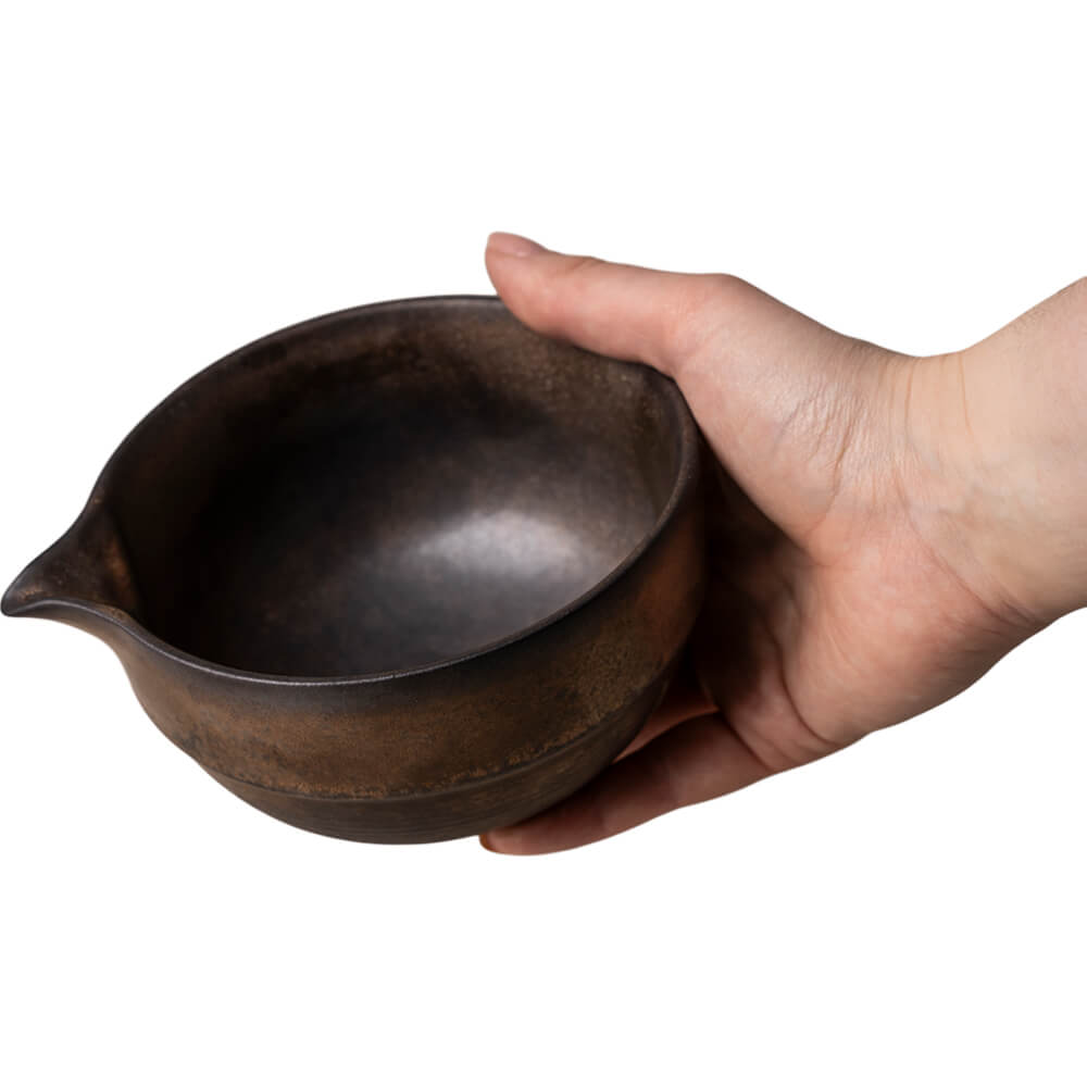 Dunkelbraune Matchaschale Pan mit Reaktivglasur und Ausguss in einer Hand gehalten