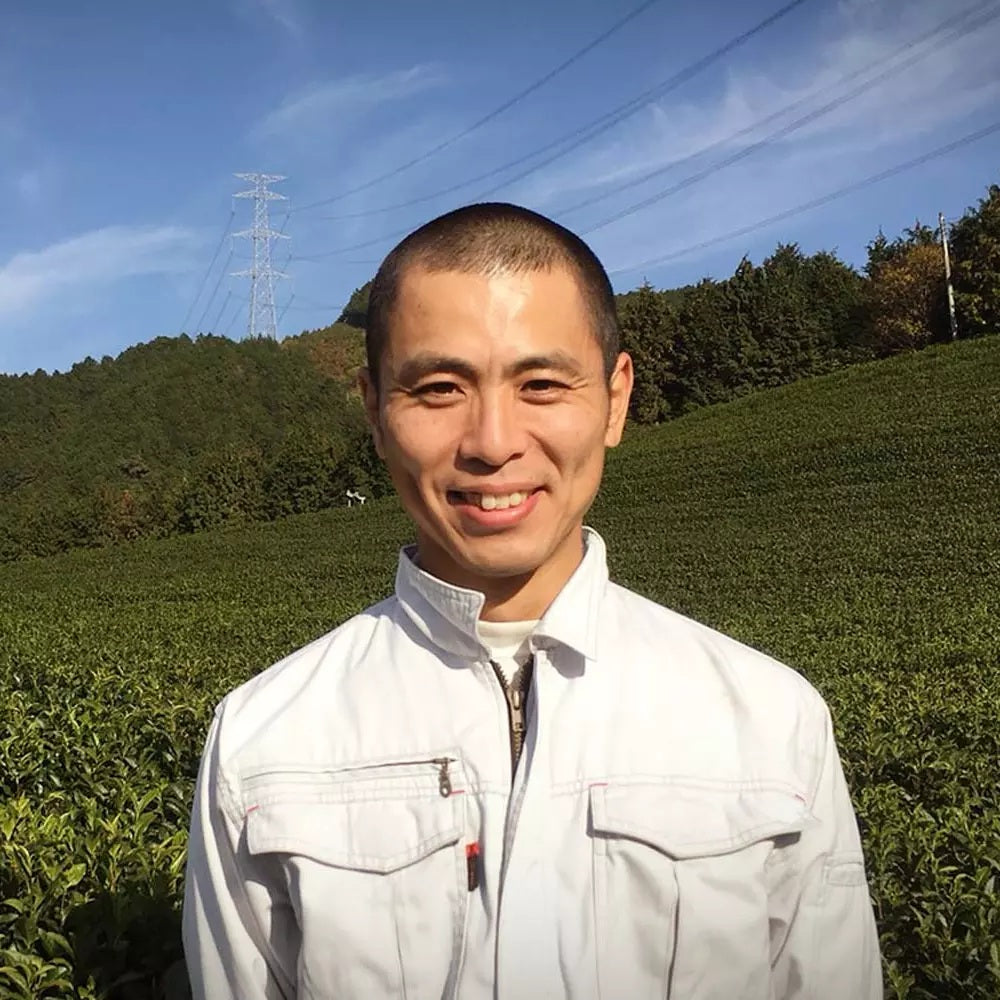 Japanischer Teebauer aus Uji vor grünen Teefeldern von der Familie Ookawa